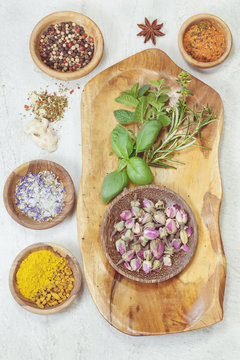 Spices and herbs  in olive wood bowls over granite table