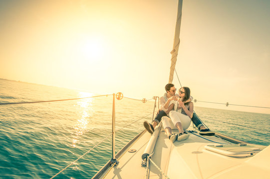 Happy couple in love on sail boat with champagne at sunset