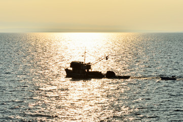 Fischkutter am Meer in untergehender Sonne