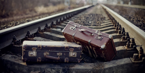 Two vintage suitcases thrown on railway rails.