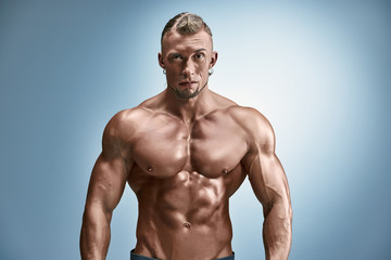 Fototapeta na wymiar Attractive male body builder on blue background