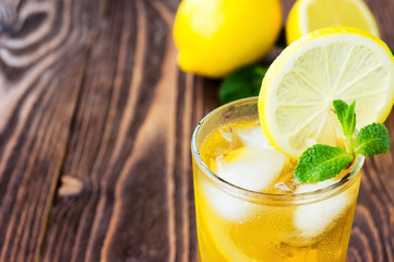 Glass of ice tea with lemons on wooden table