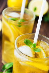 Two glasses of ice tea with ice-cubes on wooden table
