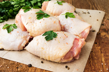 Raw chicken thighs with parsley on wooden table