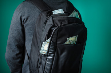 man with a black backpack from which protrude dollars
