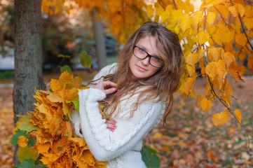Beautiful woman with glasses walks in autumn park