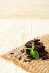 Dark chocolate with mint leaf on wooden background