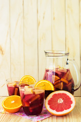 A jug of refreshing sangria with fruits on wooden background