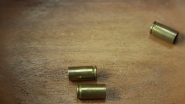 Three bullet casings falling onto wooden BG center frame
