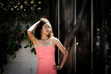 Young woman posing in pink dress with hand in hair