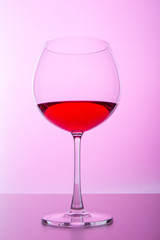 glass with wine on pink background