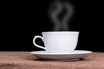 white cup with hot liquid and steam on black