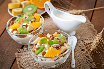 Healthy dessert with muesli and fruit in a glass bowl on the tab