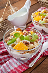 Healthy dessert with muesli and fruit in a glass bowl on the tab