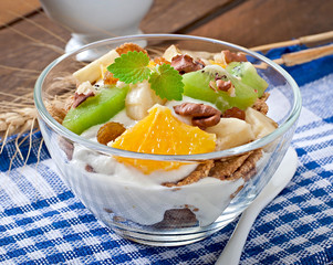 Healthy dessert with muesli and fruit in a glass bowl on the tab
