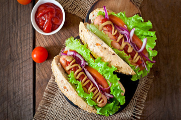Hotdog with ketchup mustard and lettuce on wooden background