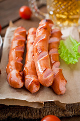 Grilled sausages, crackers and beer on a wooden background 
