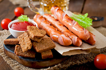 Grilled sausages, crackers and beer on a wooden background 