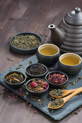 assortment of fragrant dried teas and green tea on wooden table