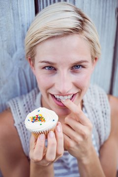 Pretty blonde woman tasting the cupcake
