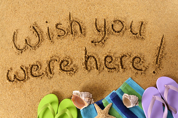 Wish you were here classic postcard or post card message written in sand on a tropical beach with...