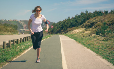 Young woman with earphones listening music and running