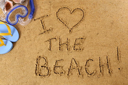 Love word text message written in sand on a tropical beach with seashells and accessories holiday vacation photo