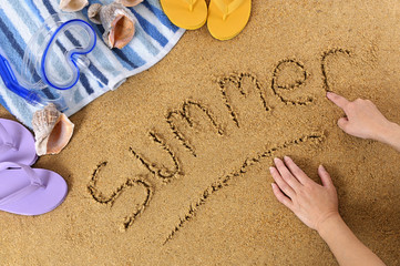 Fototapeta na wymiar Summer word message child hands writing written in sand on a tropical beach with seashells and accessories holiday vacation photo