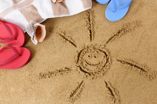 Smiling sun happy smiley face drawing drawn in sand on a tropical beach with seashells and accessories summer holiday vacation photo