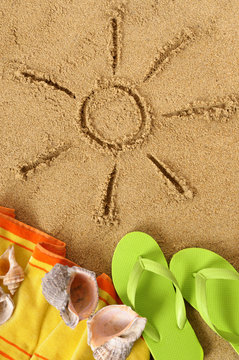 Sun sunbeam drawing drawn in sand on a tropical beach with seashells and accessories summer holiday vacation photo vertical