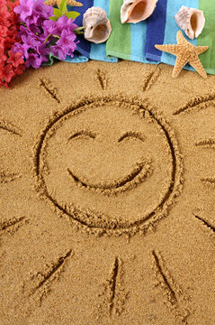 Smiling sun happy smiley face drawing drawn in sand with child hands on a hawaiian beach with seashells and accessories summer holiday vacation photo vertical