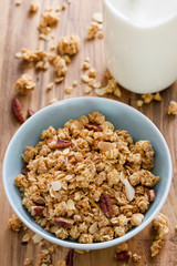 granola in bowl in brown background and bottle of milk