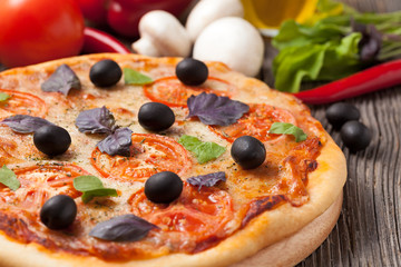 Italian pizza margherita with tomatoes, olives and basil on vint