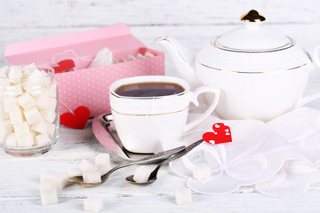Heart shaped teabag tags, box and teapot on wooden background