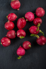 Fresh vibrant red radish on black slate background