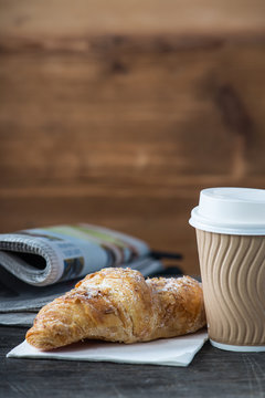 Take away coffee and fresh croissant and newspaper