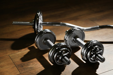 Dumbbells on wooden floor, on dark background