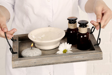 Beauty therapist holding tray of spa treatments, close-up