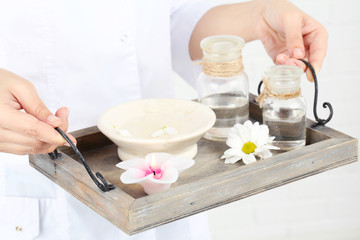 Beauty therapist holding tray of spa treatments, close-up