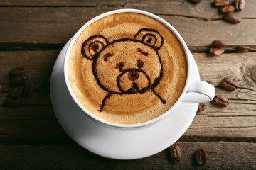 Cup of latte art coffee with grains on wooden background