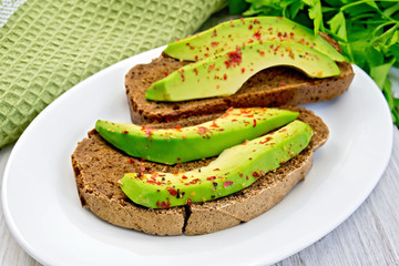 Sandwich with avocado and pepper in bowl on light board