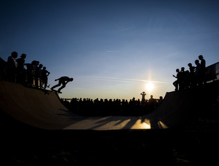 Fototapeta na wymiar Skateboarder jumping on a ramp at dusk