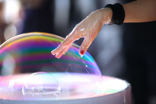 A magician pushing her hand through the bubble wall