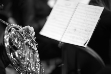 Musician hands with a french horn next to the music stand