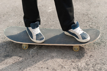 Skateboarder feet in sneakers on a skateboard.