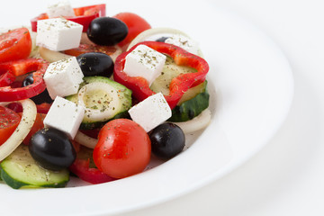 Greek salad with olives, tomato, cucumber and feta in a white di