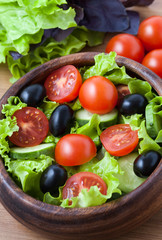 Healthy spring vegetarian salad with tomato and olives on rustic