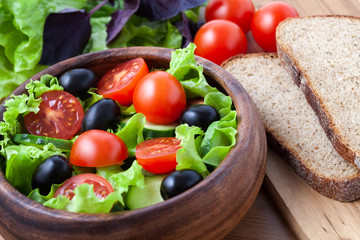 Spring vegetarian salad with tomato and olives on rustic backgro