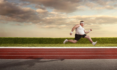 Funny overweight man speeding on the running track with copy spa