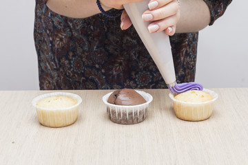 Woman decorated cupcakes with cream